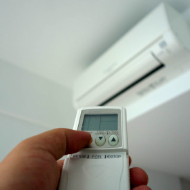 Hand holding remote control, turning on of air conditioning install air con In London UK